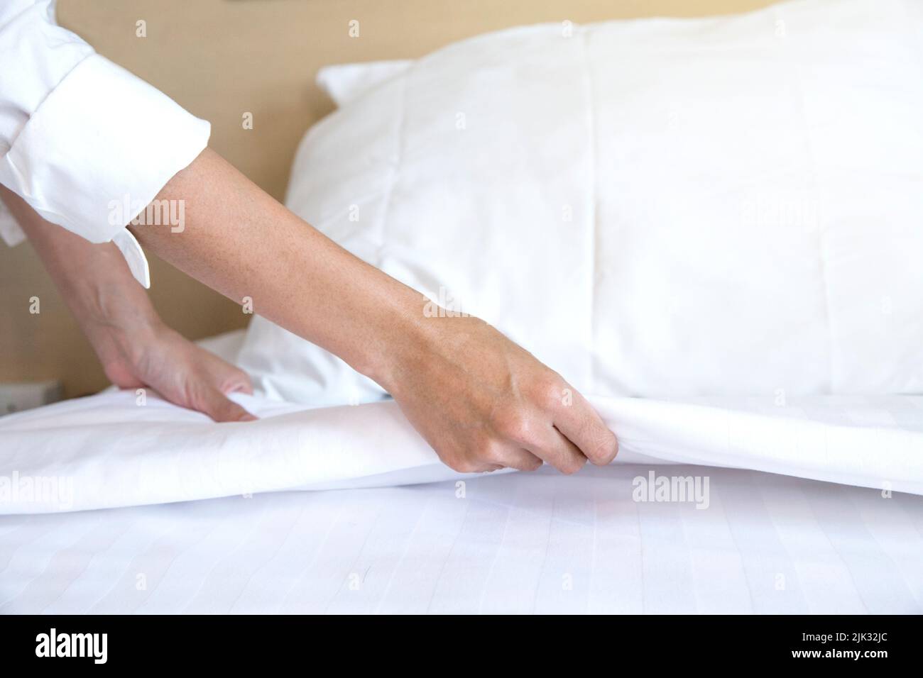 Close up hand set up white drap de lit dans chambre d'hôtel Banque D'Images