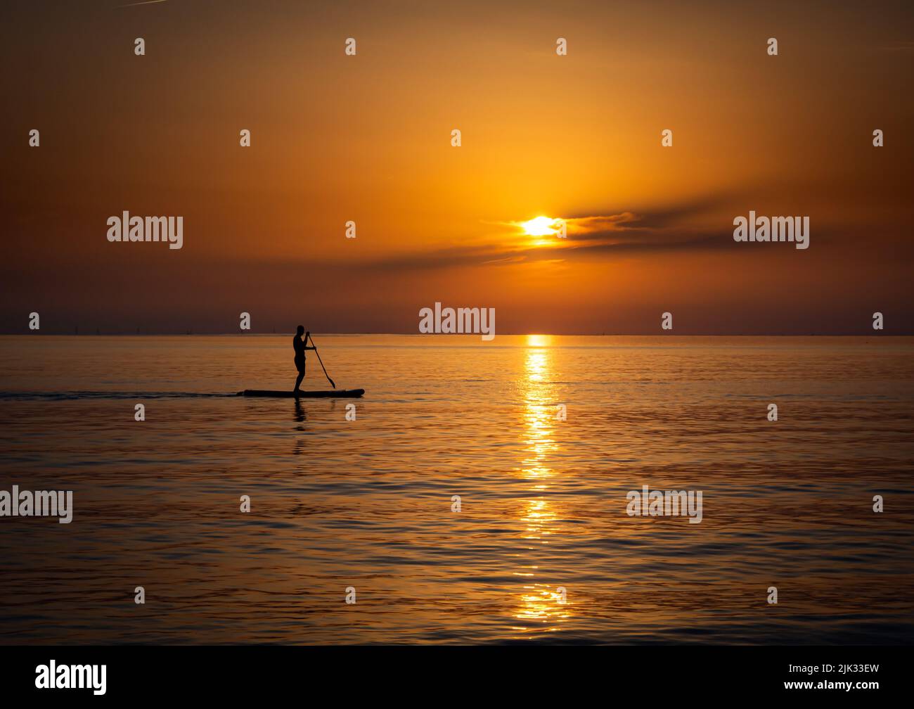 La silhouette d'un homme paddle-board devant le coucher du soleil Banque D'Images