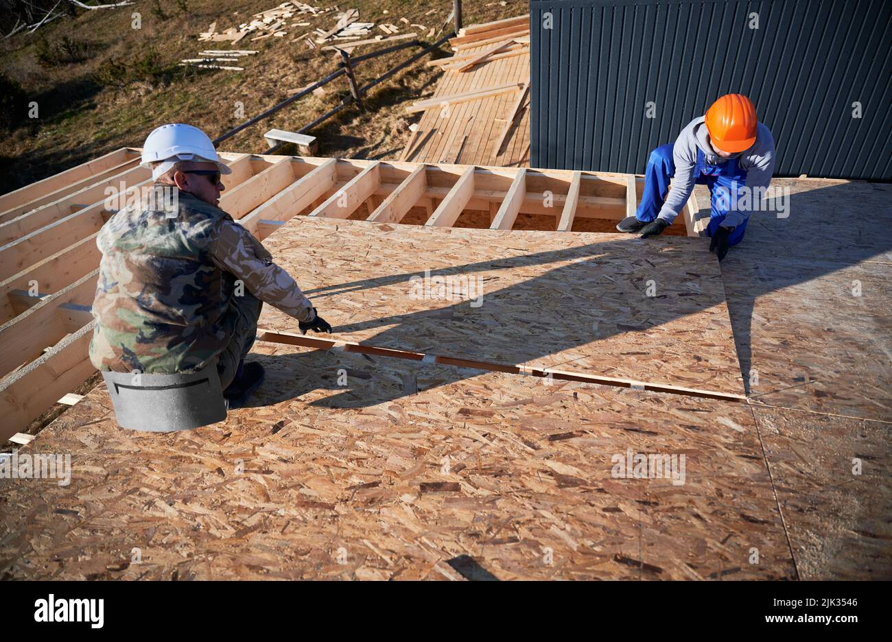 Charpentiers de montage de panneaux OSB en bois sur le toit du futur chalet. Hommes ouvriers construction maison en bois. Conception de la menuiserie et de la construction. Banque D'Images