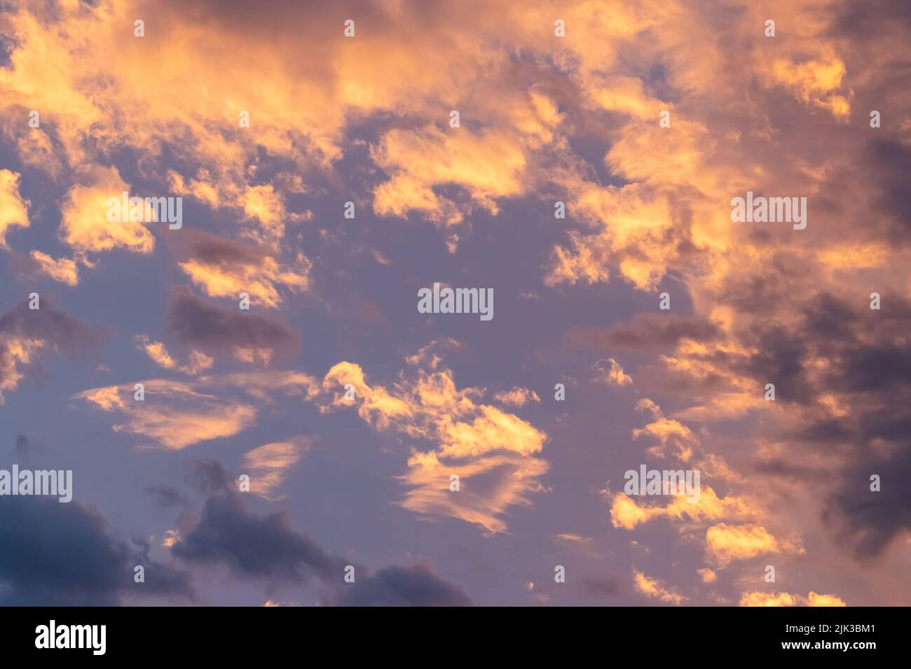 Ciel violet avec des nuages orange et jaune moelleux au coucher du soleil. Banque D'Images