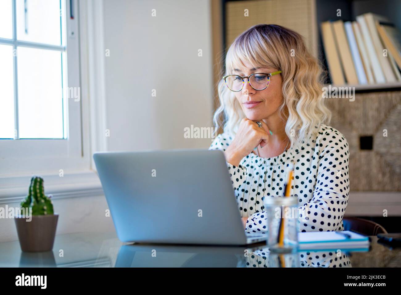 Femme entrepreneur indépendante moderne travaillant sur un ordinateur portable dans un bureau de studio à domicile. Bonne femme souriant devant l'ordinateur faisant un appel vidéo confere Banque D'Images