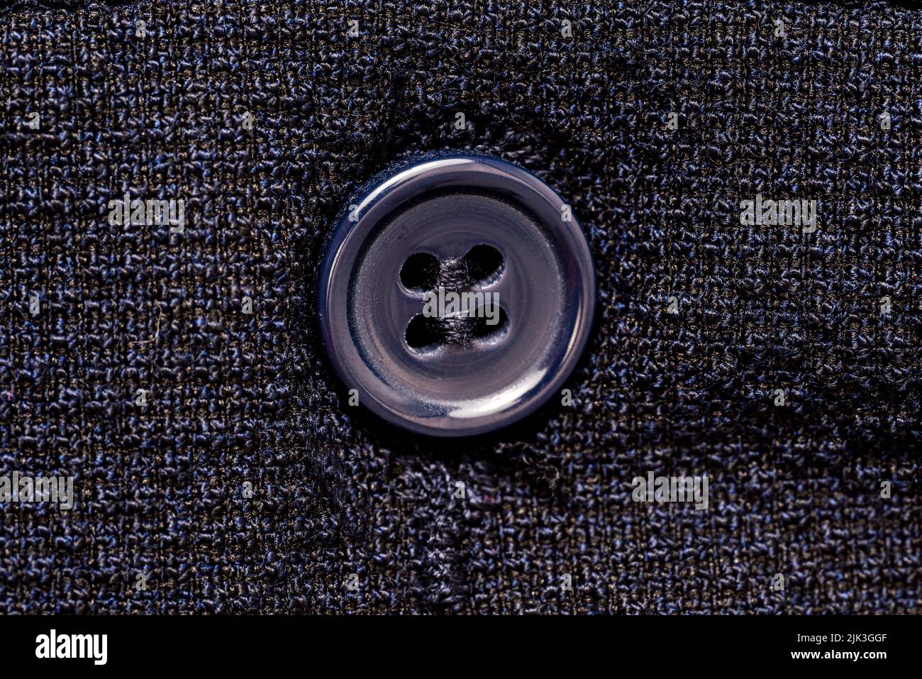 Photo macro d'un bouton à coudre sur un fond isolé de motif en tissu bleu foncé. Photo de haute qualité Banque D'Images