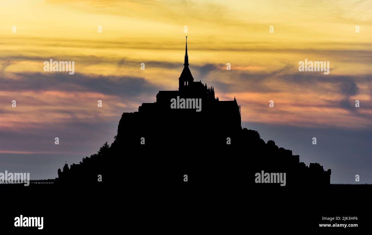 Silhouette du Mont Saint-Michel au coucher du soleil sur fond de coucher de soleil. Banque D'Images