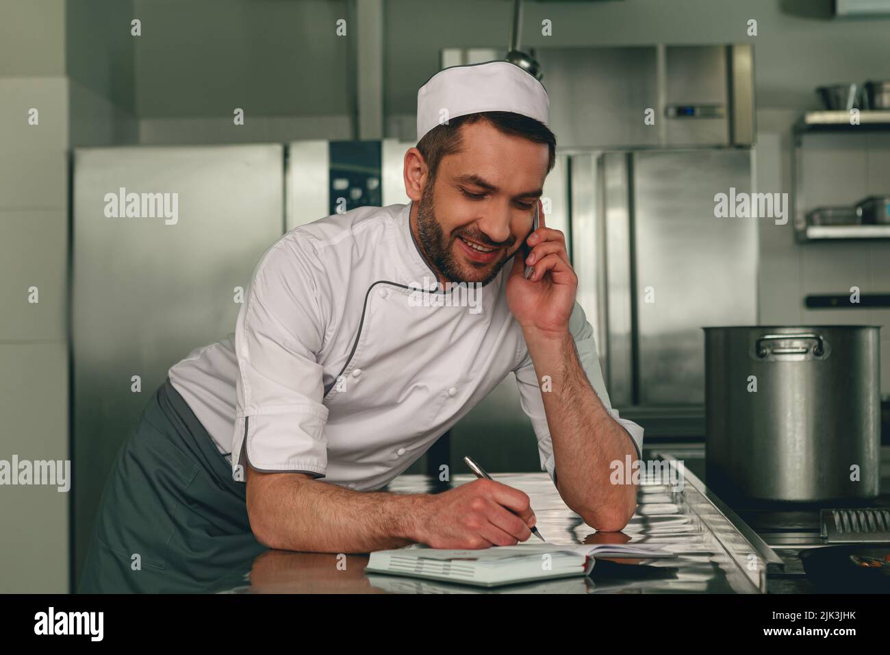 Chef souriant en uniforme en ordre pour le fournisseur debout sur la cuisine Banque D'Images