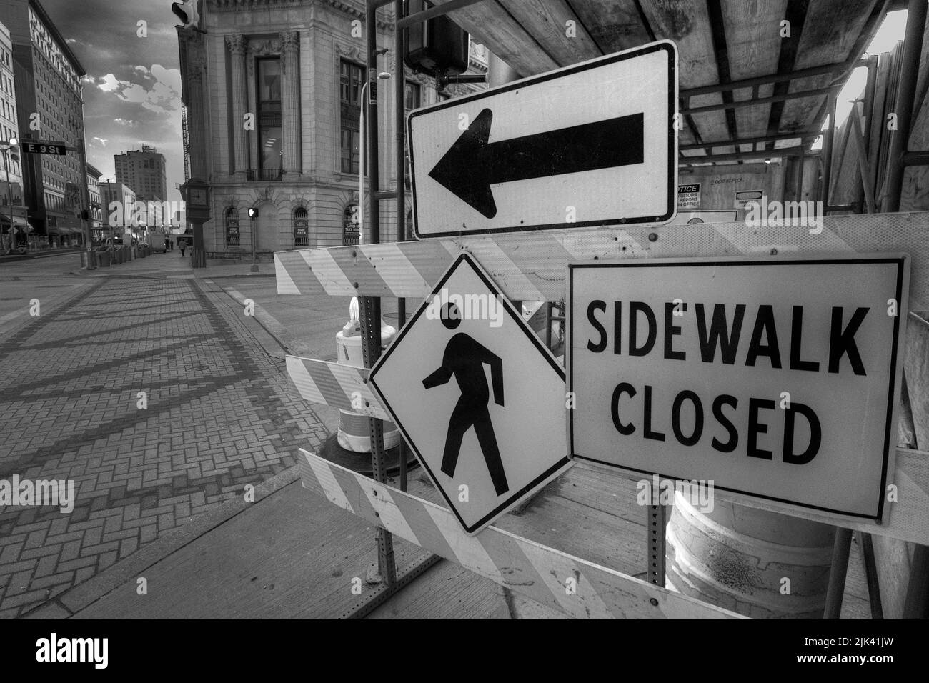 Image de ville en noir et blanc des panneaux indiquant que le trottoir est fermé et un autre itinéraire Banque D'Images