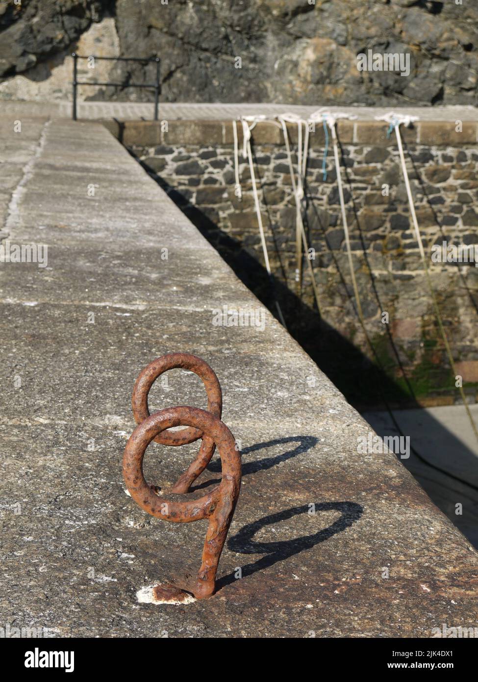 99 problèmes et la plage ain't One: Deux anneaux de mouillage rouillés sur le mur du port à Mullion Cove, Cornwall, Royaume-Uni, forment un nombre involontaire Banque D'Images