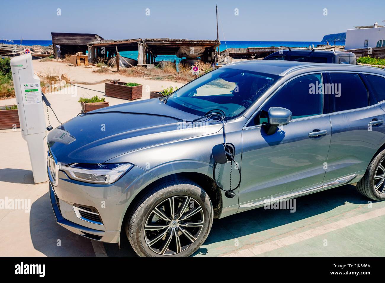 Ibiza, espagne - 25 juillet 2022 : une voiture électrique recharge sa batterie sur un poteau à côté d'une plage en vacances. Banque D'Images