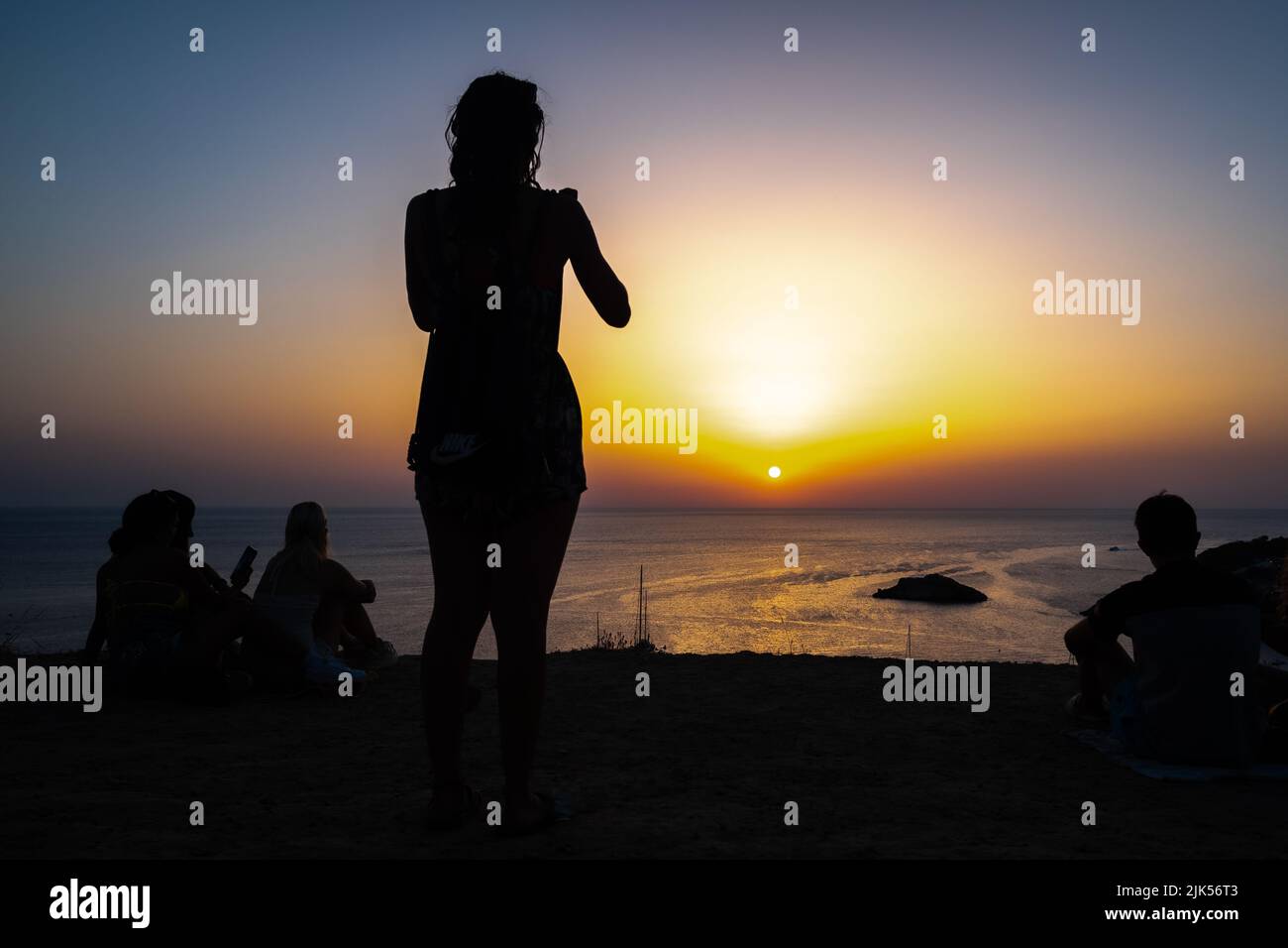 Femme aime le coucher du soleil sur la rive d'une plage paradisiaque pendant les vacances d'été. Banque D'Images