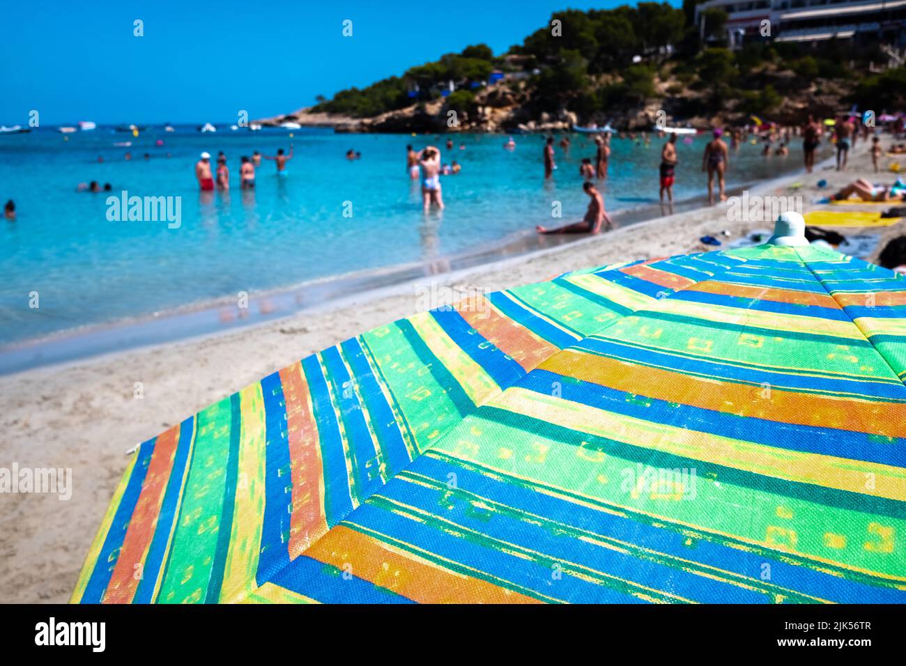 Les vacanciers profitent d'une journée ensoleillée à la plage, un arrière-plan hors du foyer avec parasol en premier plan. Banque D'Images