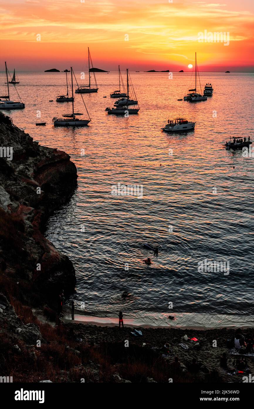 Plusieurs bateaux de plaisance ancrés dans une crique sur l'île d'Ibiza pour admirer le coucher du soleil. Banque D'Images