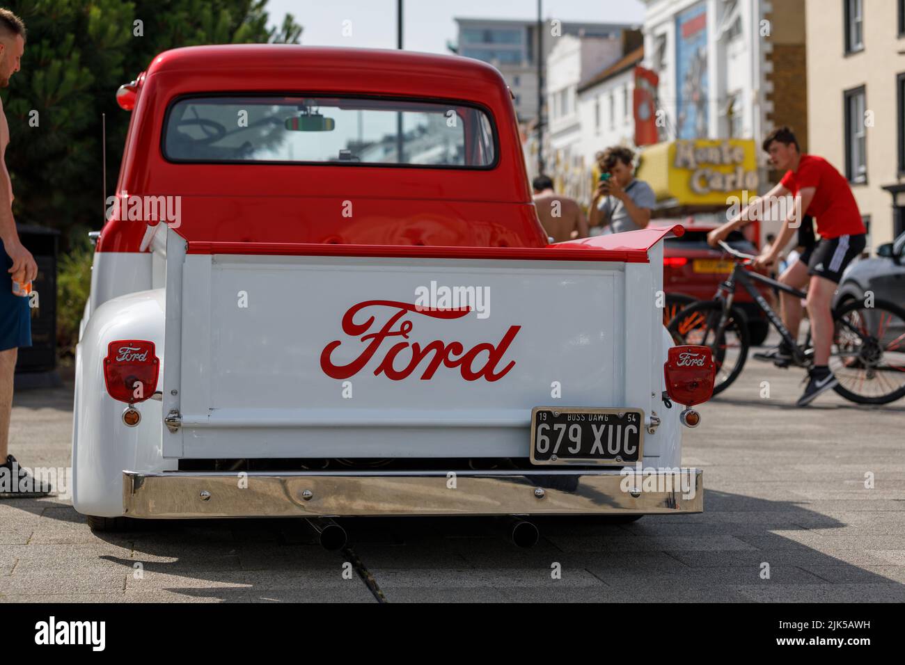 Un camion de pick-up personnalisé Ford F100 des années 1950 en rouge et blanc. Vue arrière. Garé dans une rue avec les piétons. Banque D'Images