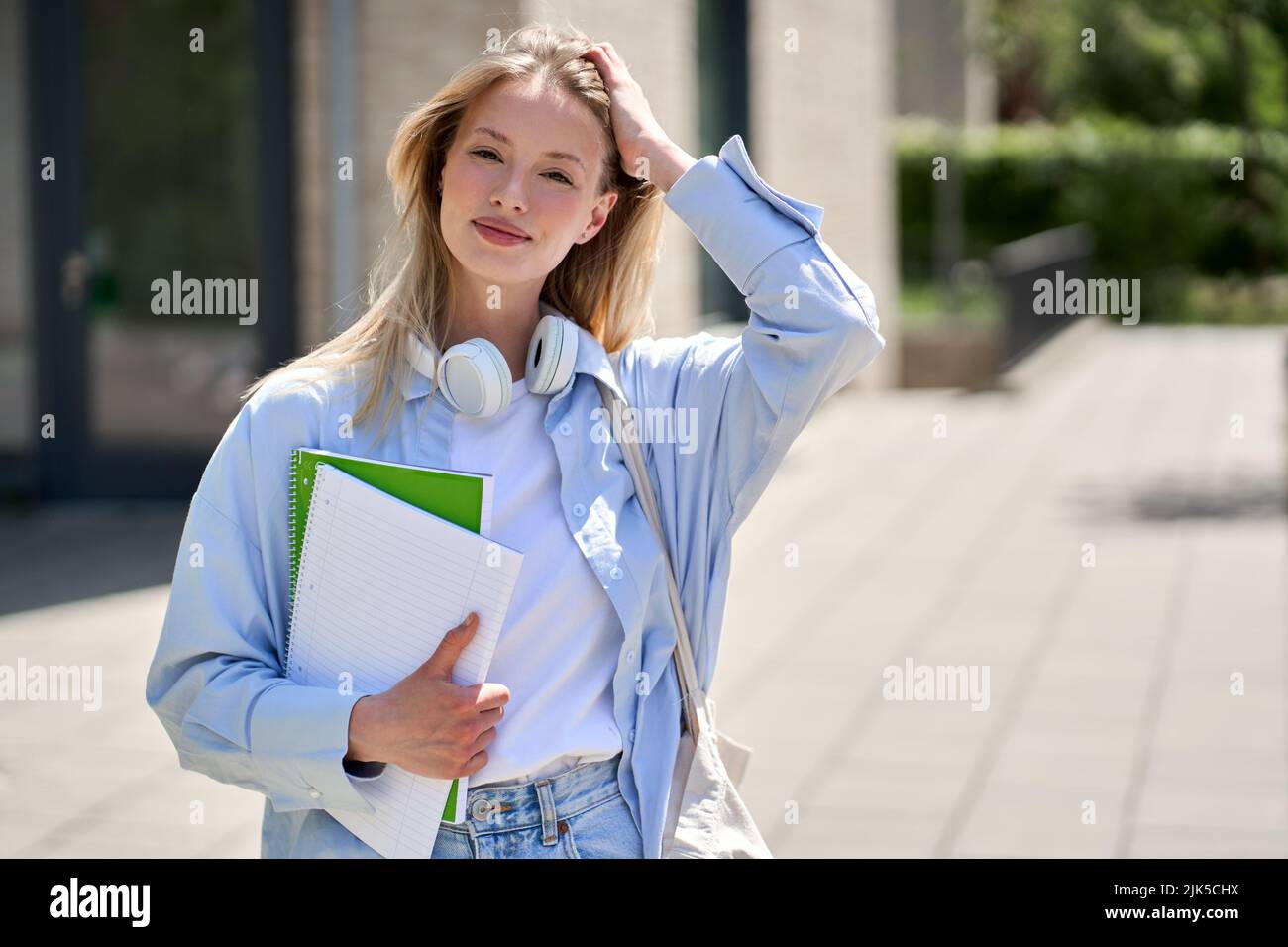 Jolie fille souriante étudiant de l'université tient des cahiers debout à l'extérieur, portrait. Banque D'Images