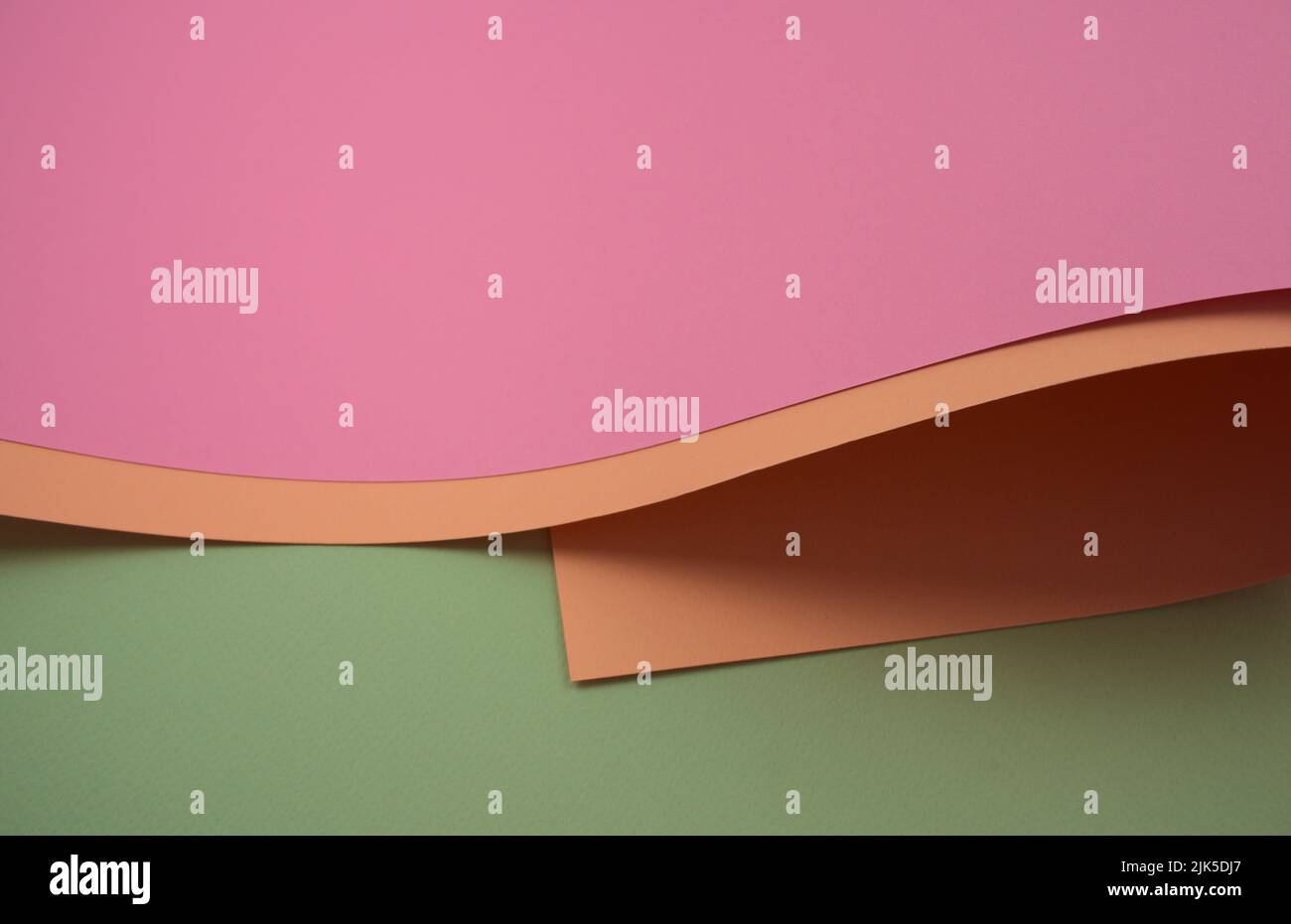 Papier abstrait aux couleurs courbes élégantes. Papiers colorés rose pastel, rose ancien et vert clair. Horizontal, sans personne, style d'image grand angle. Banque D'Images