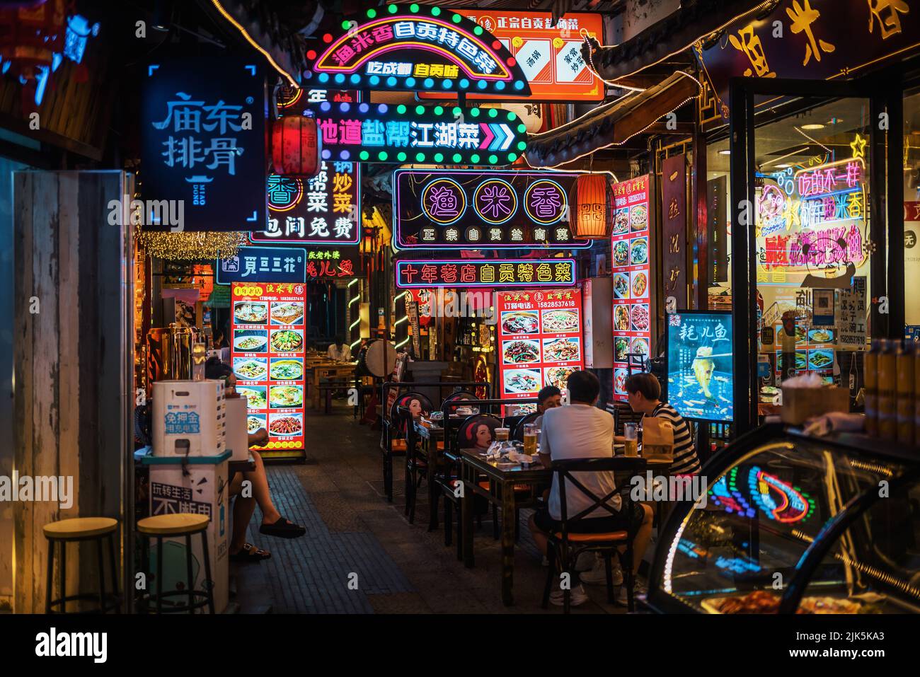 Les personnes qui mangent sur les terrasses des restaurants chinois la nuit avec des lumières au néon Banque D'Images