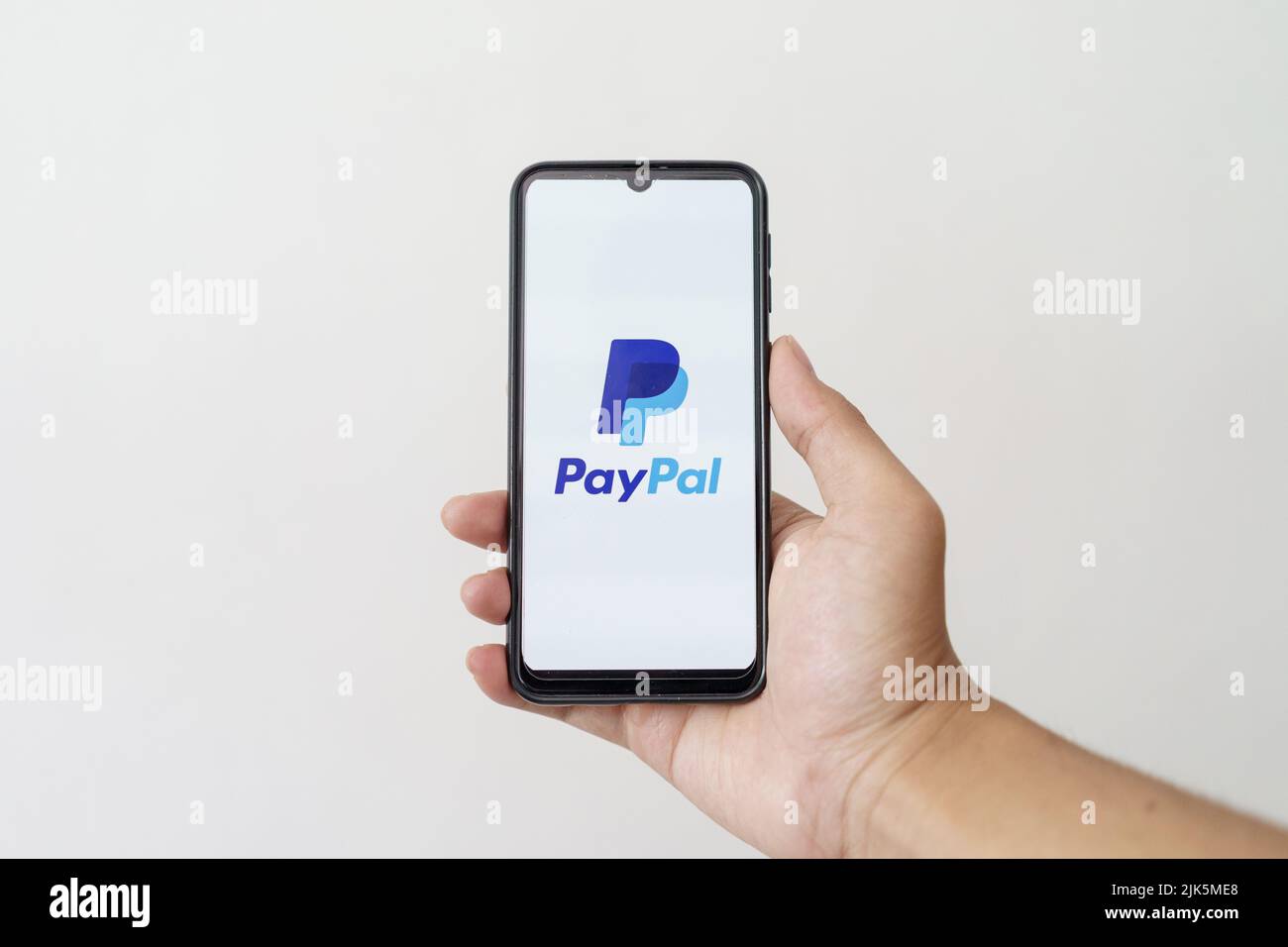 Une main tient le smartphone avec le logo PayPal. Banque D'Images