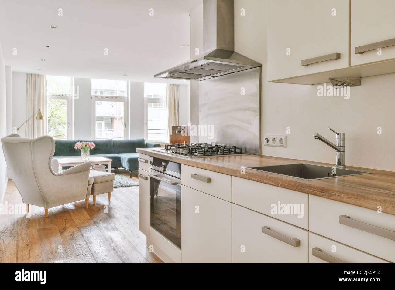 Décoration intérieure contemporaine minimaliste de ce studio lumineux avec table et chaises en bois dans la salle à manger entre la cuisine ouverte et le salon avec murs blancs et parquet Banque D'Images