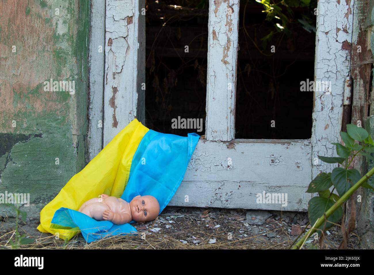 Une poupée d'enfants se trouve sur les drapeaux de l'Ukraine dans une maison à explosion de missiles, la guerre en Ukraine, la mort d'enfants de missiles russes Banque D'Images
