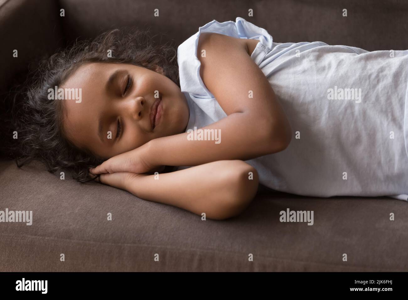 Adorable petite fille indienne sur un canapé confortable Banque D'Images