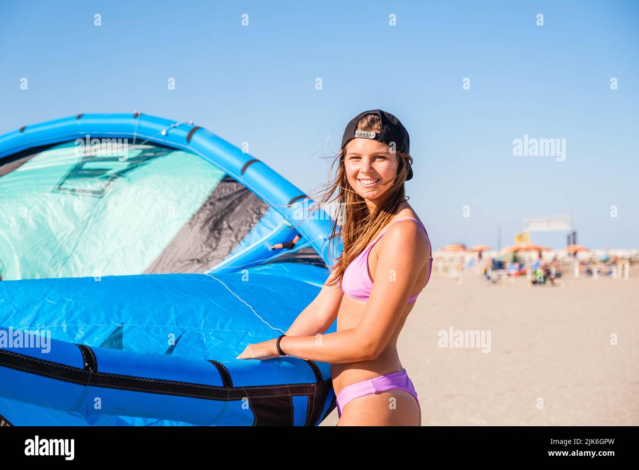 Belle fille de surf cerf-volant en maillot de bain bikini rose avec cerf-volant dans la mer bleue. Activités récréatives, sports nautiques, action, passe-temps, fitness en été Banque D'Images