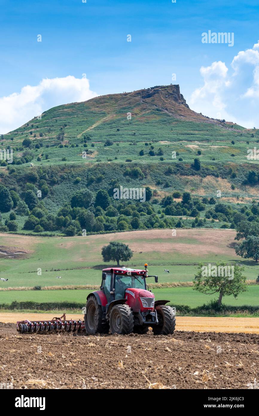 Tracteur McCormick cultivant un lit de semence sur le bord des Moors de North York, avec une garniture de roseberry en arrière-plan. Yorkshire, Royaume-Uni. Banque D'Images