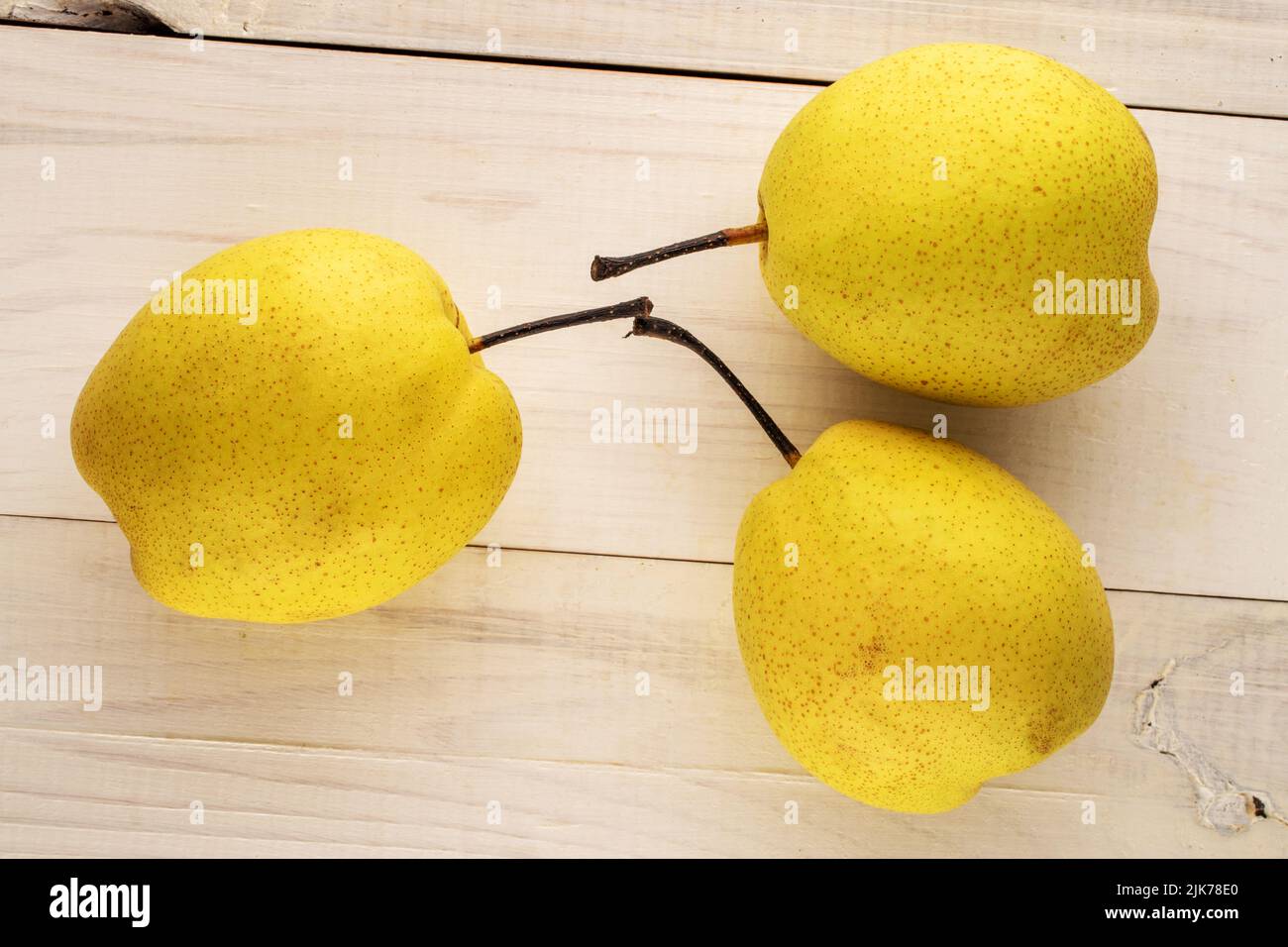 Trois poires jaune vif sur une table en bois, vue rapprochée, vue de dessus. Banque D'Images