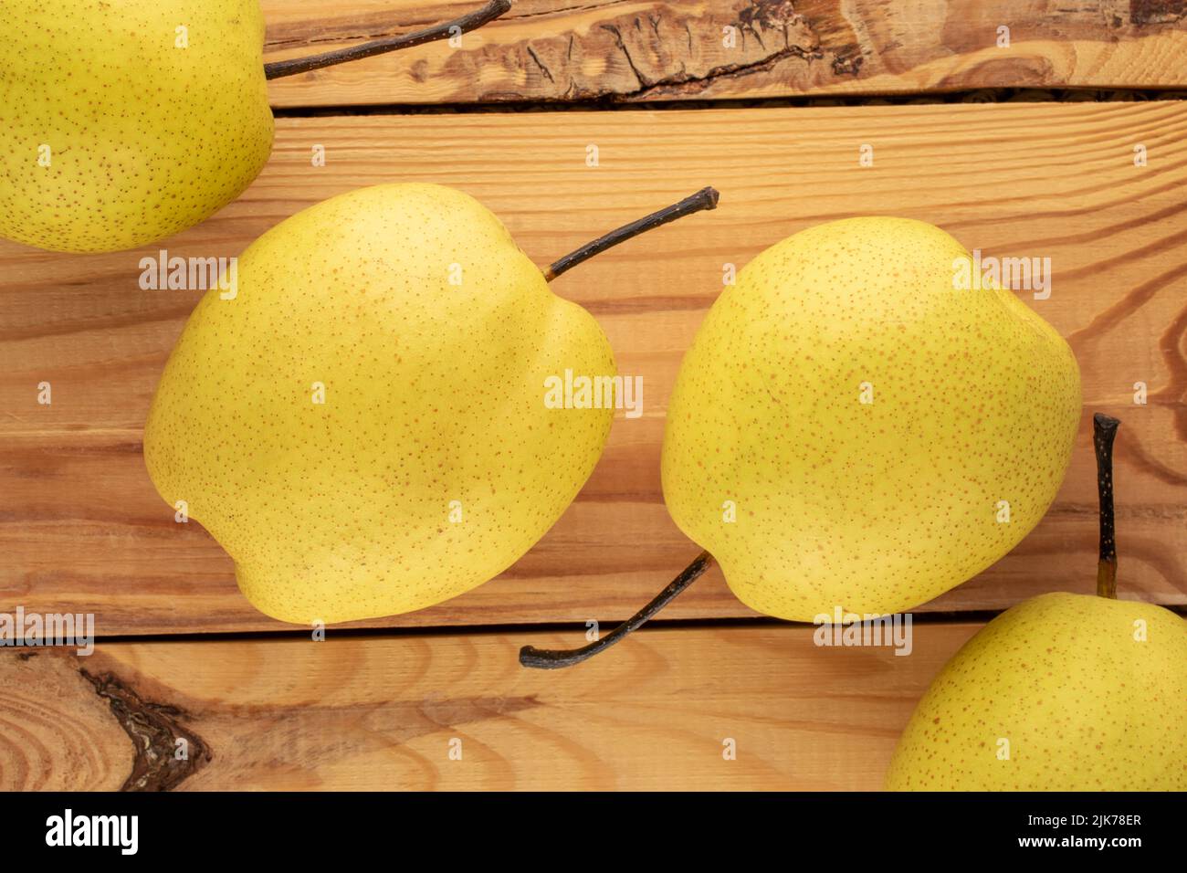 Quatre poires jaune vif sur une table en bois, vue rapprochée, vue de dessus. Banque D'Images
