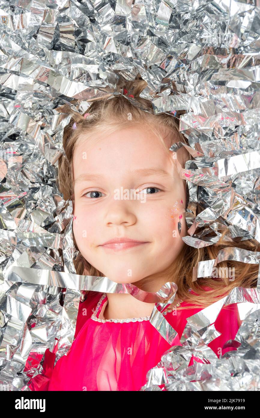 Visage souriant et joyeux d'une fille dans une énorme pile de confetti en feuille d'argent, gros plan. Une fille en paillettes étincelantes. Joyeux anniversaire, Noël, Nouveau Banque D'Images