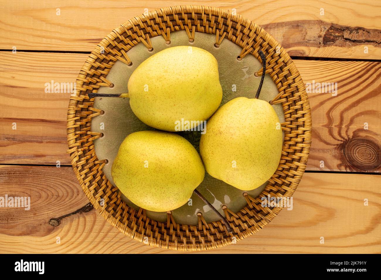 Trois poires jaunes douces dans une assiette en céramique sur une table en bois, vue rapprochée, vue de dessus. Banque D'Images