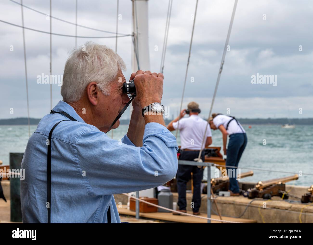 spectateur à la régate annuelle de la semaine des cowes regardant à travers des jumelles à la course de yacht, regardant les raxces sur l'île de wight à la semaine des cowes. Banque D'Images