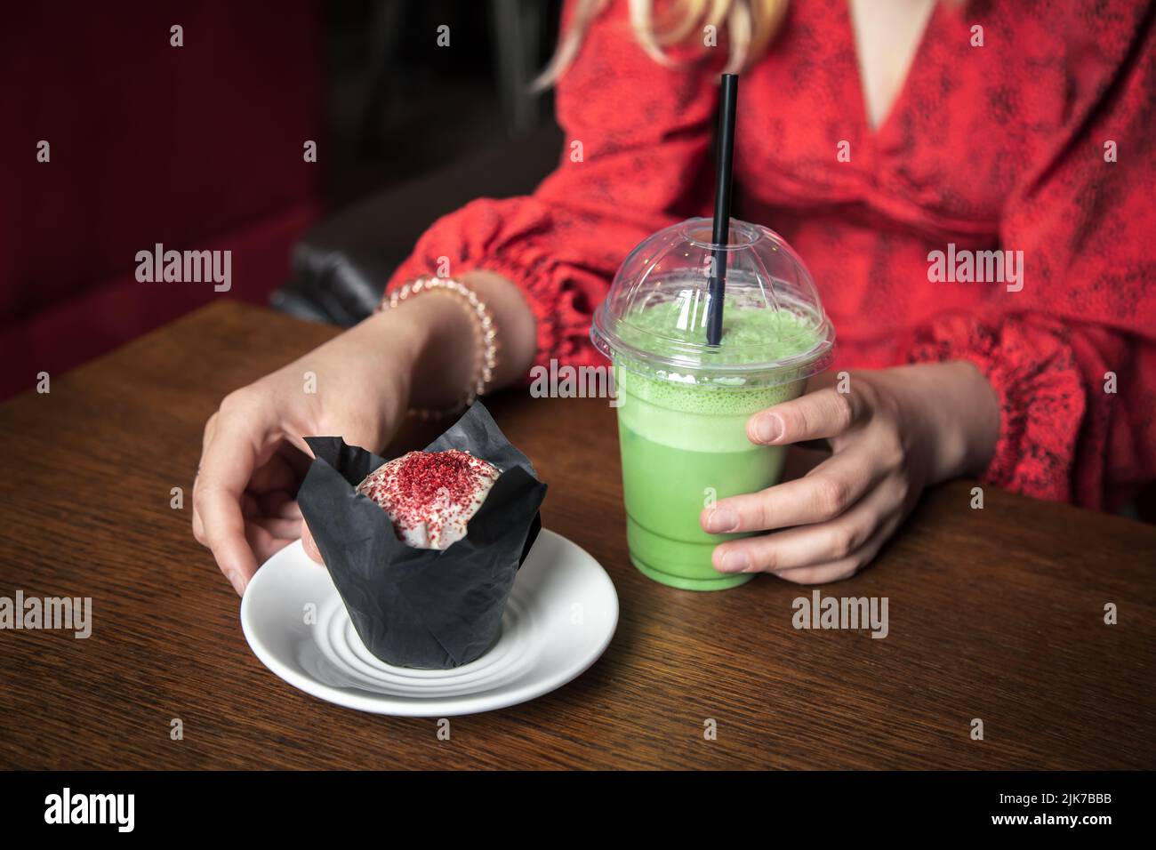 Latte au matcha glacé et gros gâteau dans un café entre les mains des femmes. Banque D'Images