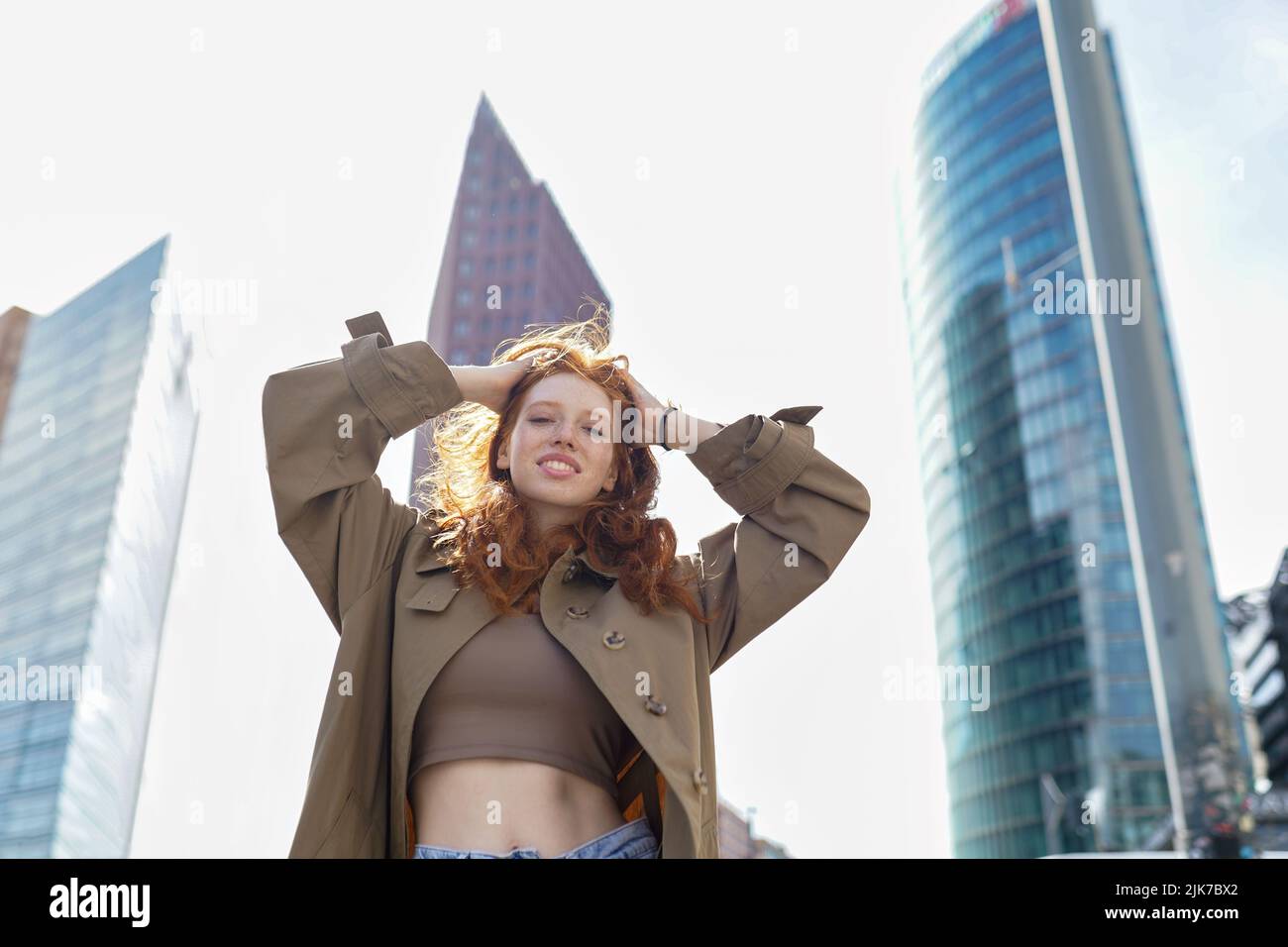 Bonne adolescente redhead debout sur la grande ville urbaine rue regardant la caméra. Banque D'Images