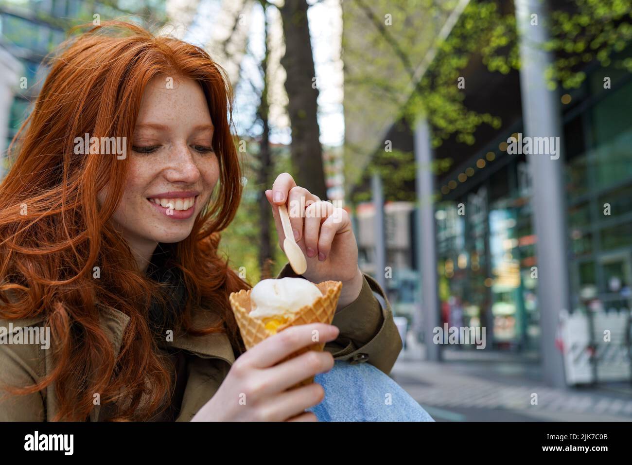 Une jeune fille hipster souriante et fraîche mange de la glace dans la rue urbaine de la grande ville. Banque D'Images