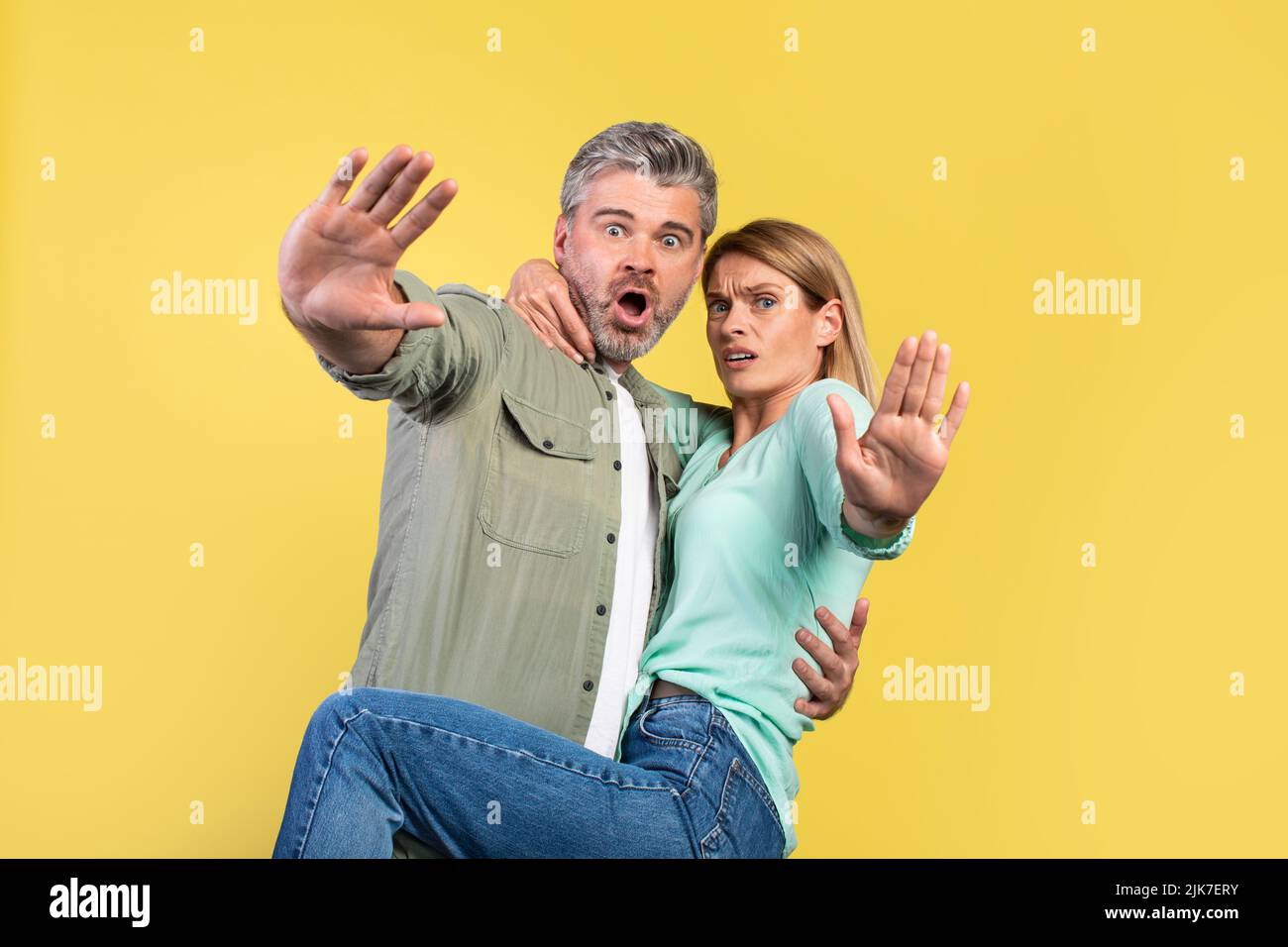 Guide d'utilisation Portrait de conjoints d'âge moyen effrayés hurlant et gesturant arrêt, femme sautant sur mari, regardant l'appareil photo Banque D'Images