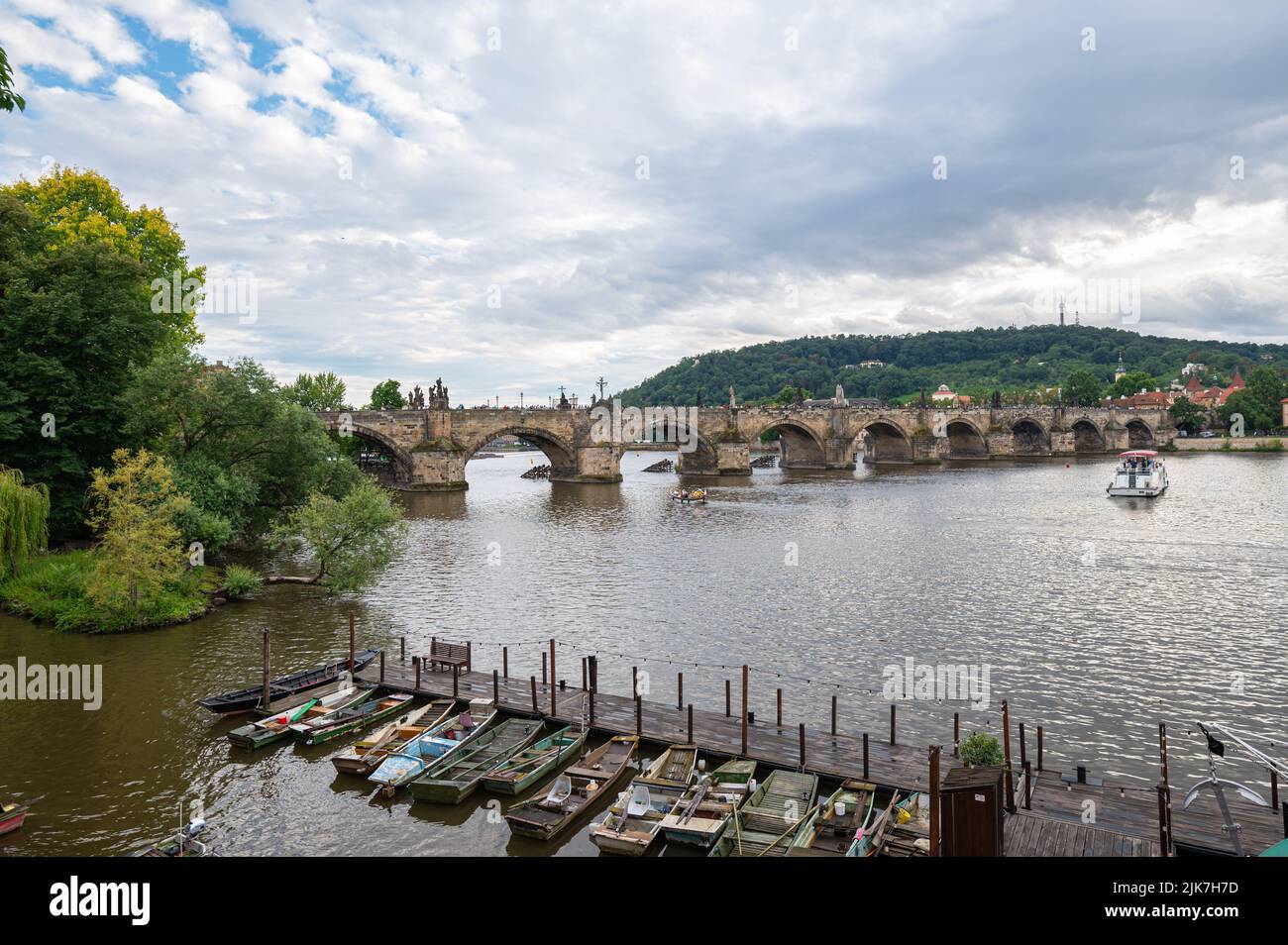 Vue panoramique sur le pont Charles (tchèque: Karlův Most) dans la ville de Prague avec de petits bateaux en bois au premier plan. Banque D'Images