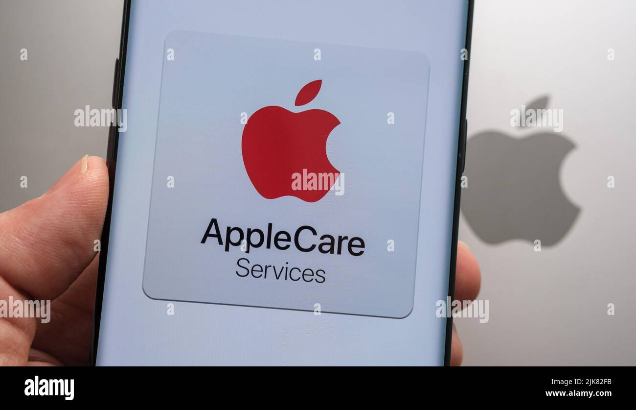 Logo Apple Care Services visible sur le smartphone tenez la main au-dessus du haut du macbook avec le logo Apple flou. Concept. Stafford, Royaume-Uni, 3 juillet Banque D'Images