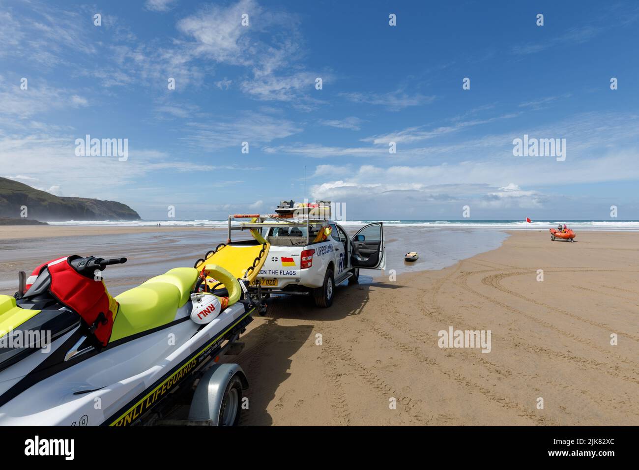 RNLI LifeGuards sur la plage. Un camion de patrouille RNLI se trouve sur une plage de Cornwall, en Angleterre, avec un coureur de vagues sur une remorque Banque D'Images