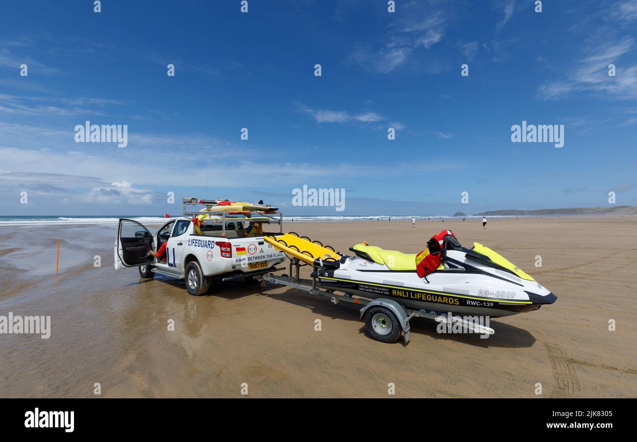 Sauveteurs sur la plage. Un camion de patrouille RNLI se trouve sur la plage avec un coureur de vagues sur une remorque derrière Banque D'Images