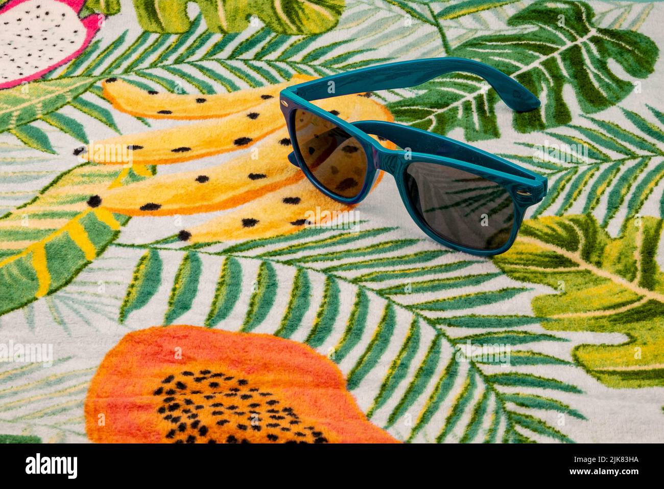 Lunettes de soleil bleues sur une serviette hawaïenne. Banque D'Images