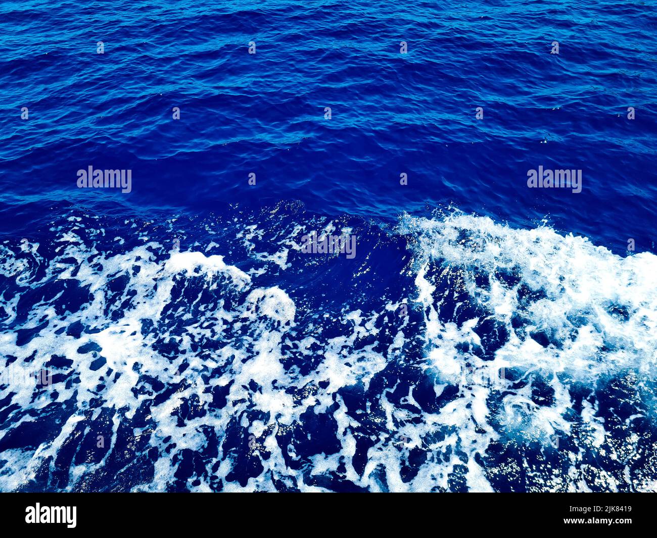 Surface bleu profond d'eau de mer transparente avec des glints solaires Banque D'Images