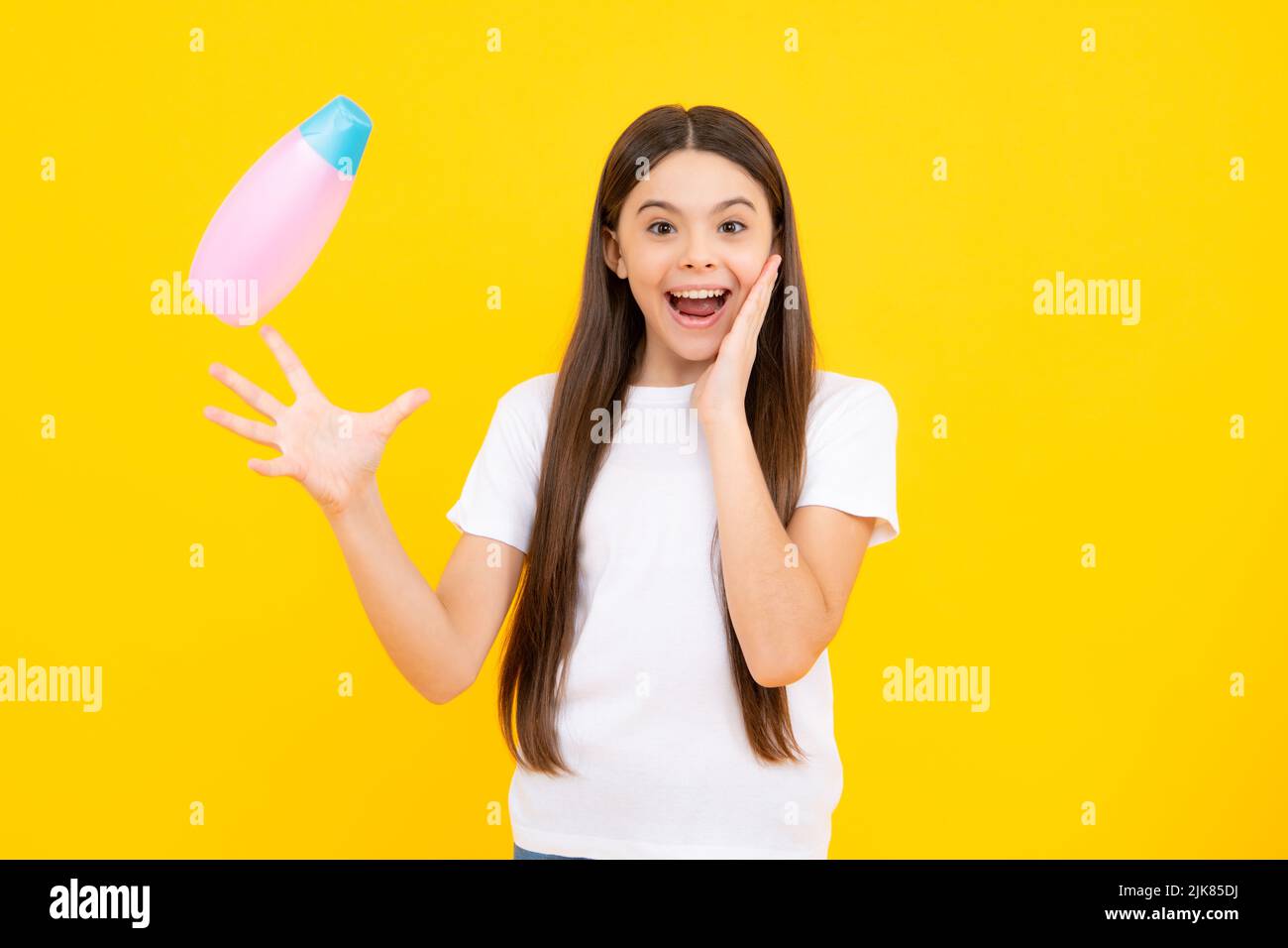Portrait heureux de l'enfant avec après-shampooing. Soins cosmétiques quotidiens. L'adolescent de 12, 13, 14 ans tient une bouteille de soins pour les cheveux et la peau. Beauté hea Banque D'Images