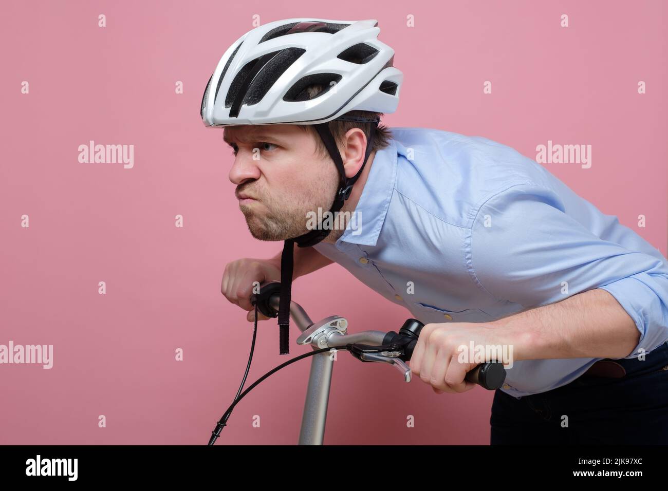 Homme caucasien confus portant sur le vélo sur fond coloré Banque D'Images