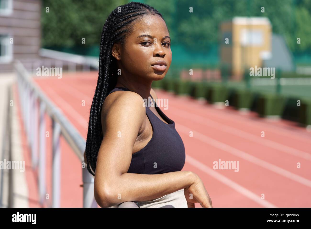 La jeune femme afro-américaine s'appuie sur une clôture métallique de terrain de sport d'un grand complexe résisentiel Banque D'Images