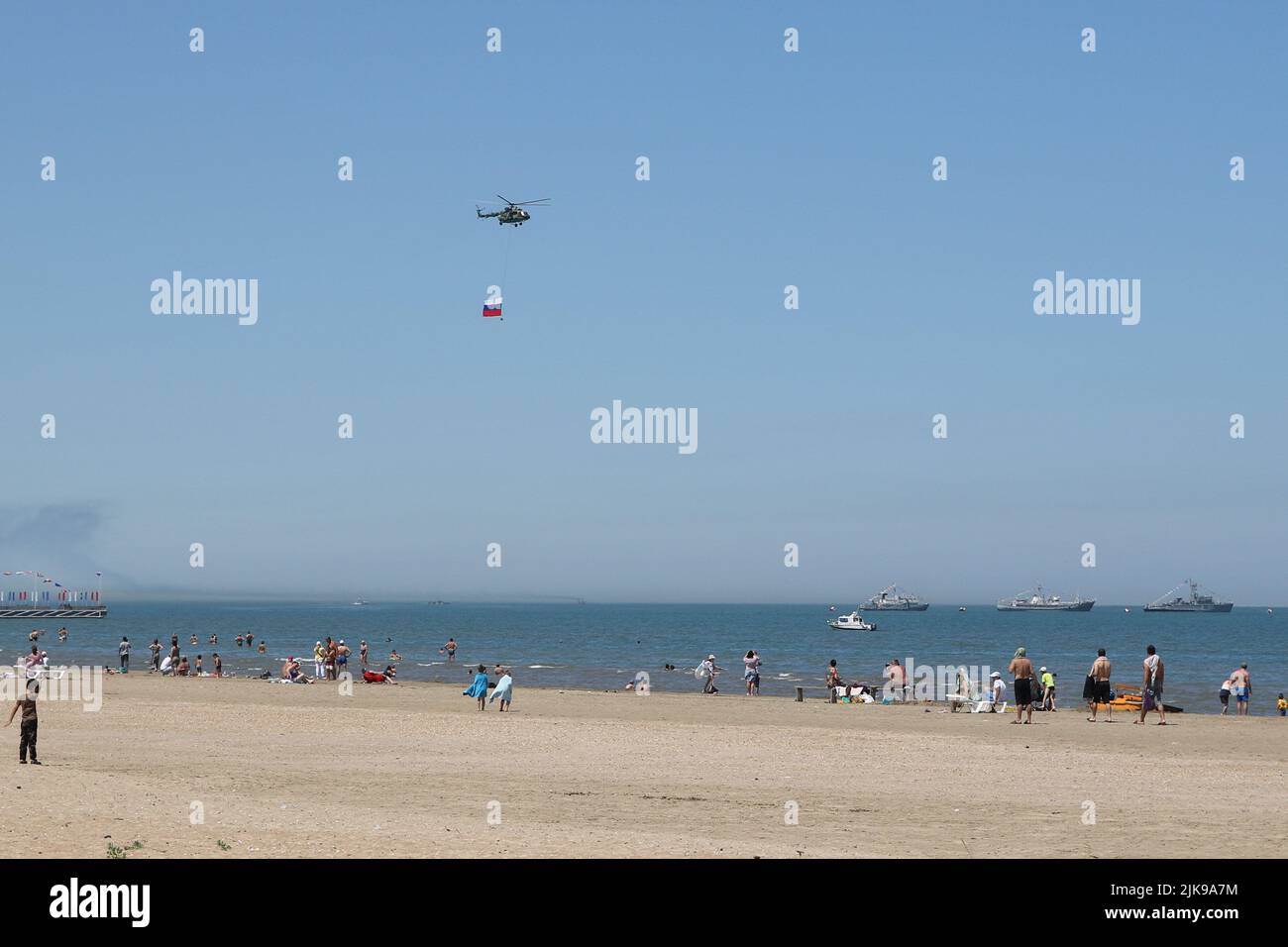 Kaspiysk, Russie. 31st juillet 2022. Les vacanciers sur les rives de la mer Caspienne regardent le défilé en l'honneur du jour de la Marine de la Fédération de Russie, un hélicoptère militaire avec le drapeau de la Fédération de Russie survole la plage de Kaspiysk. Le tourisme est en développement en Russie dans le pays pendant les sanctions de divers pays. Crédit : SOPA Images Limited/Alamy Live News Banque D'Images