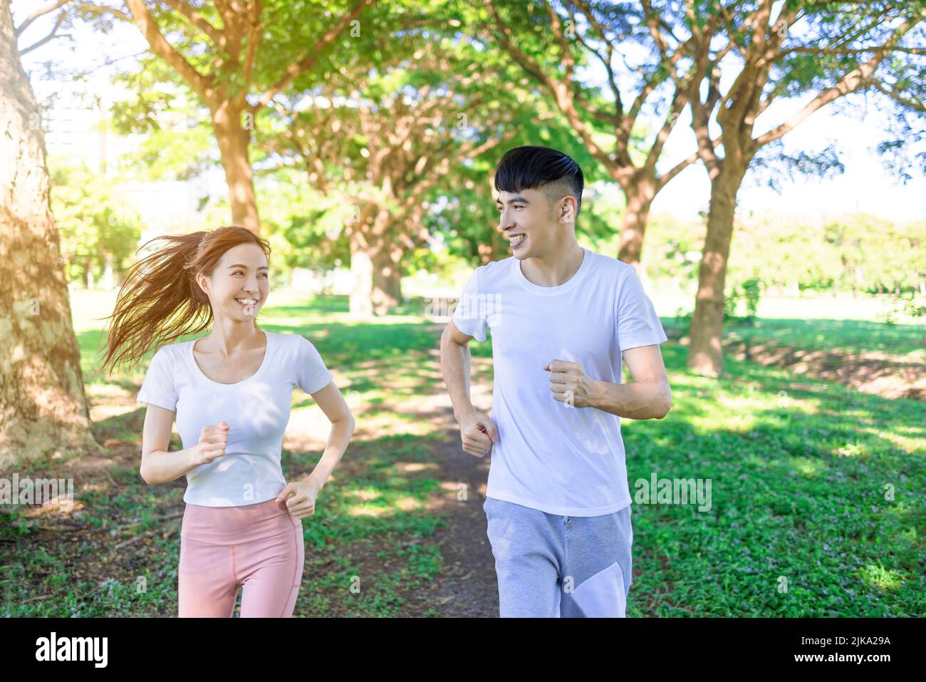 Joyeux jeune couple de jogging dans le parc par beau temps Banque D'Images