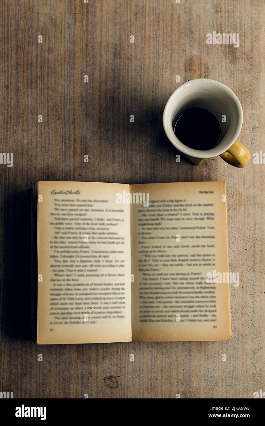 Un livre ouvert avec des pages floues et une tasse de café sur une table en bois. Mélancolie Banque D'Images