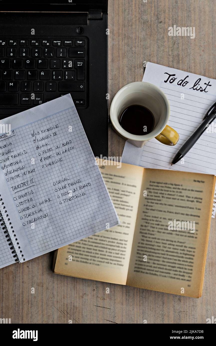 Ordinateur portable, ordinateur portable, stylo, livre, tasse de café et liste de tâches sur une table en bois. Banque D'Images