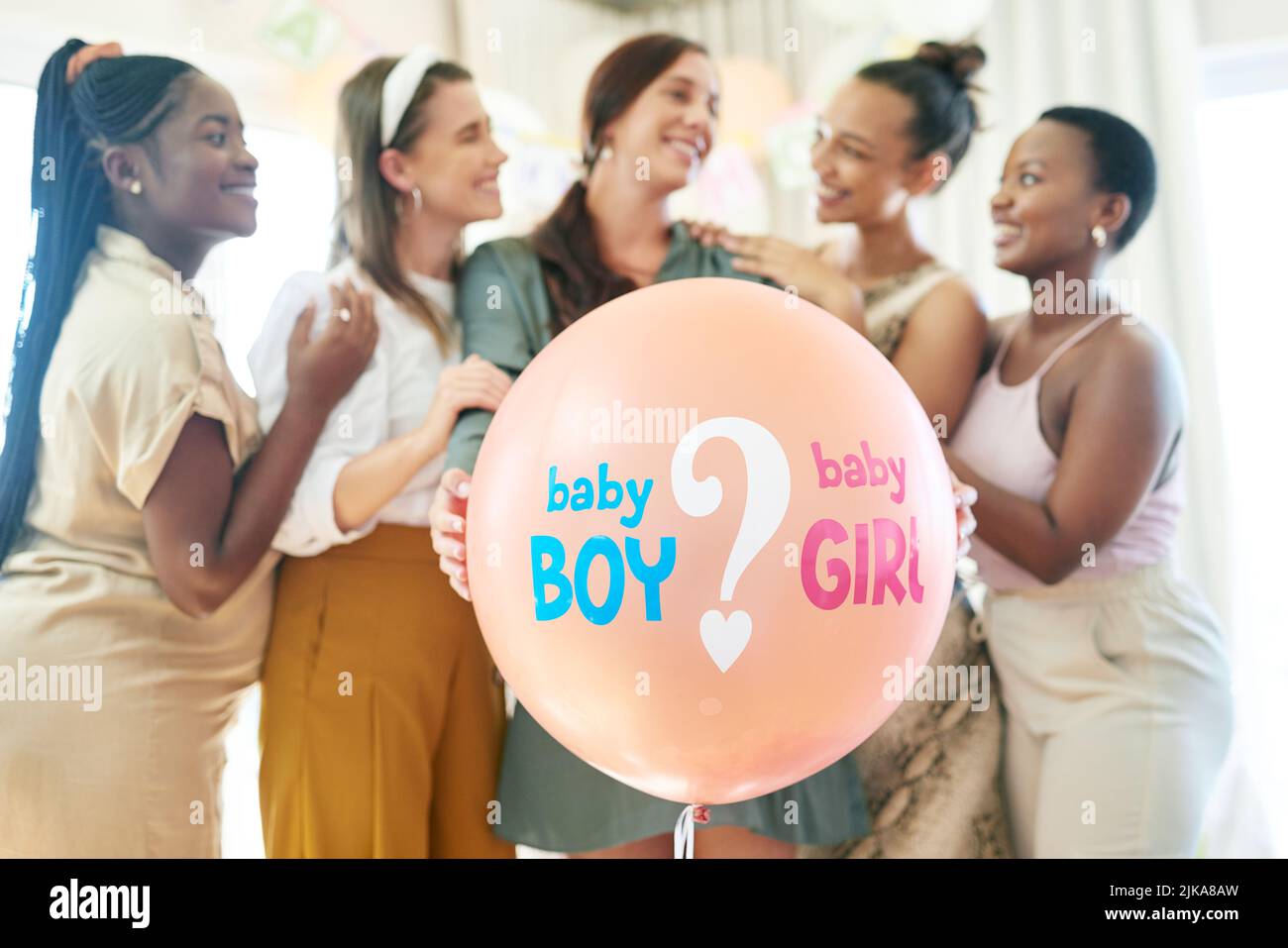 Un groupe de femmes sur le point de faire apparaître un ballon pour un genre pendant une douche de bébé. Banque D'Images