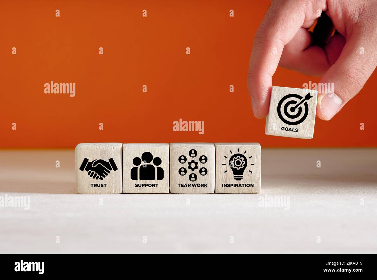Réalisation des objectifs de l'entreprise, collaboration et concept de travail d'équipe. Main place le cube en bois avec le symbole de but cible à côté des cubes avec confiance, support Banque D'Images