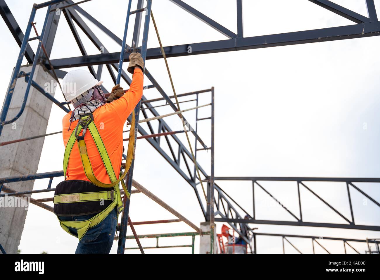 Les ouvriers de la construction travaillent sur des fermes de toit en acier avec dispositif antichute pour les travailleurs avec des crochets pour harnais de sécurité sur le siège de construction Banque D'Images