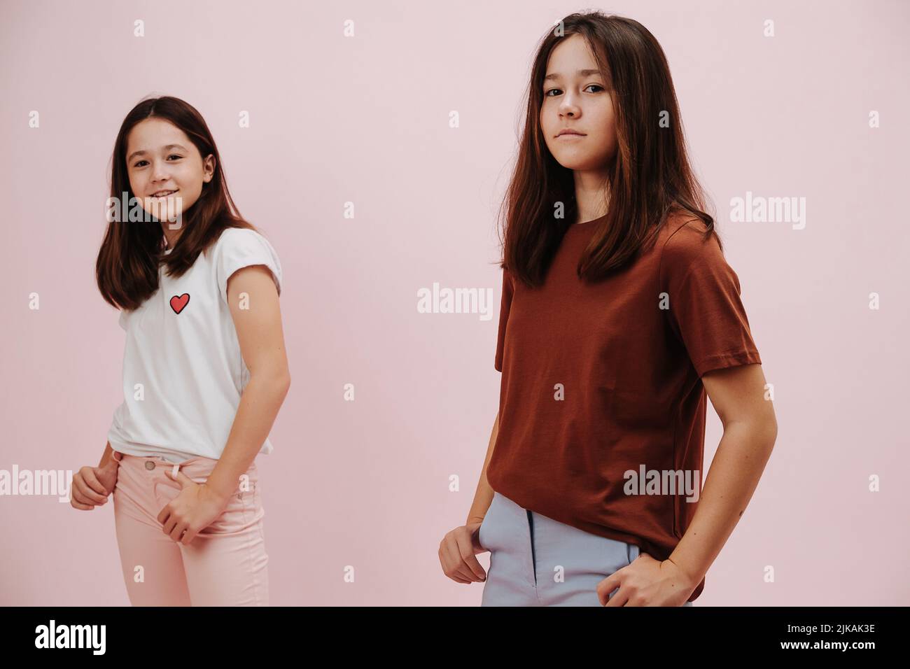 Portrait de deux filles jumelles confiantes vêtues de différentes couleurs posant Banque D'Images